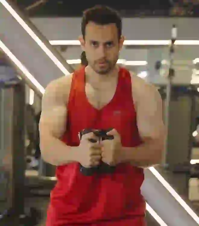 Man squeezing the Nooncrazy twister arm trainer together at chest height in a gym